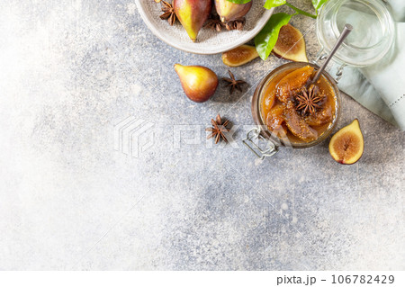 Homemade fig sweet jam in a glass jar with fresh figs on a light gray table. Autumn harvest preservation, healthy fermented food. View from above. Copy space. 106782429