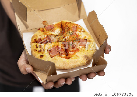 A human hand holding pizza on a cardboard box 106783206