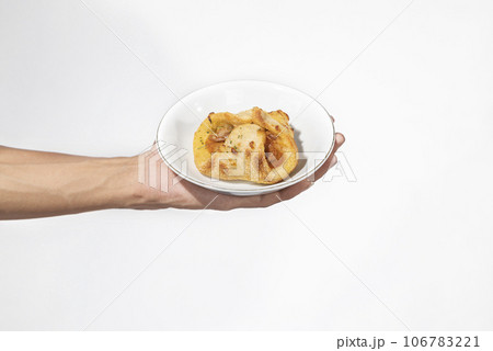 A human hand holding a side dish on a plate 106783221