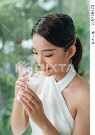 Woman with glass of milk sits by the window 106786272