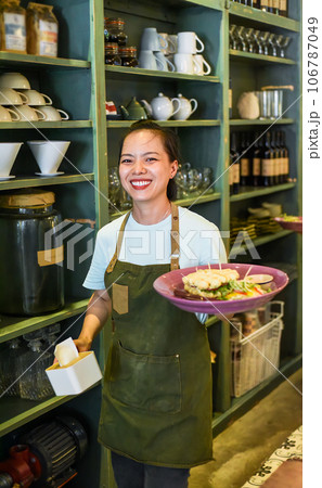 Vietnamese waitress serving belgian waffles with salad in a cafe Vietnamese waitress serving belgian waffles with salad in a cafe 106787049
