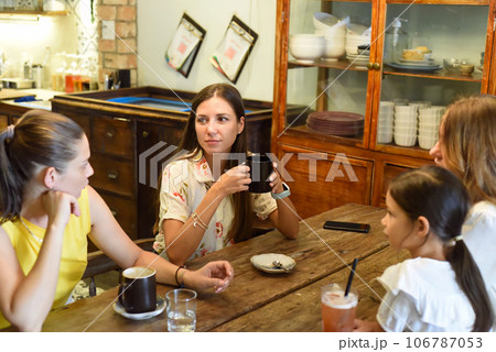 Female best friends talking and eating in a cafe 106787053