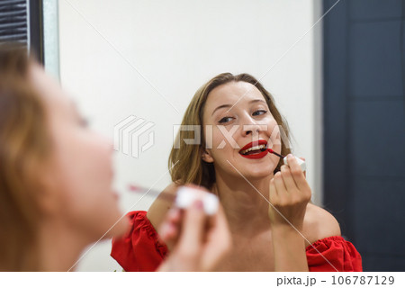 Blond beautiful woman aplying a red lipstick and looking at the mirror 106787129
