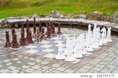 Large wooden chess pieces on board outside 106787137