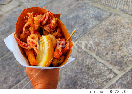 Typical Italian appetizer (Fritto misto di pesce) mix of fried seafood i female hand. Healthy snack in Genoa, Cinque Terre and Portofino 106789205