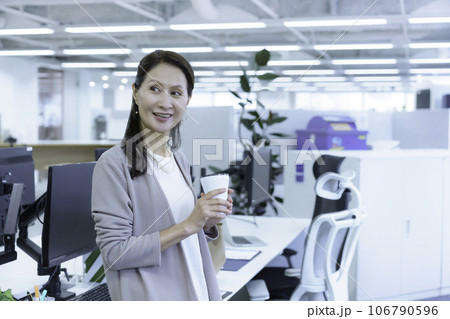 オフィスのデクスに腰掛けてタンブラーを持つシニアビジネスウーマンのポートレート オフィスのデクスに腰掛けてタンブラーを持つシニアビジネスウーマンのポートレート 106790596