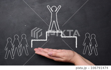 Hand holding a chalk drawing of a podium with a person on top and people on either side. The person on top is drawn with their arms raised in a victory pose. Hand holding a chalk drawing of a podium with a person on top and people on either side. The person on top is drawn with their arms raised in a victory pose. 106791474