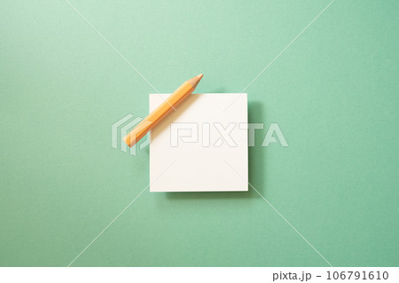 White memo paper, sticky note pad with colored pencil on green background. top view, copy space 106791610