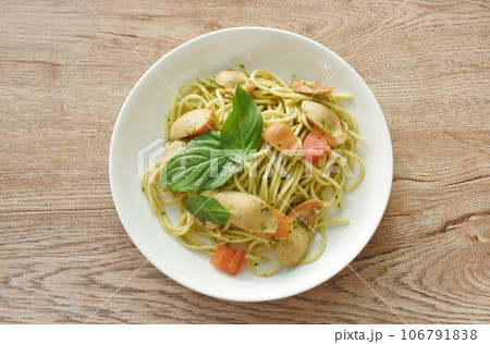 pesto spicy stir fried spaghetti with slice sausage and basil sauce on plate  106791838