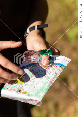 Woman holding a map and the compass during orienteering competitions. Woman holding a map and the compass during orienteering competitions. 106792118