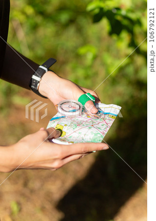 Woman holding a map and the compass during orienteering competitions. 106792121