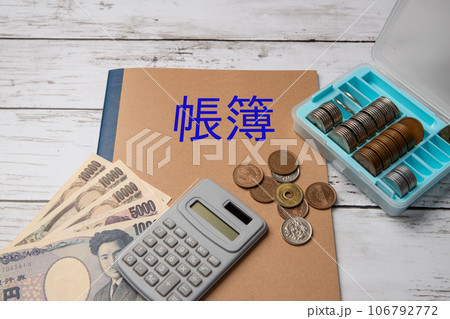 会計帳簿と現金と電卓のイメージ 106792772