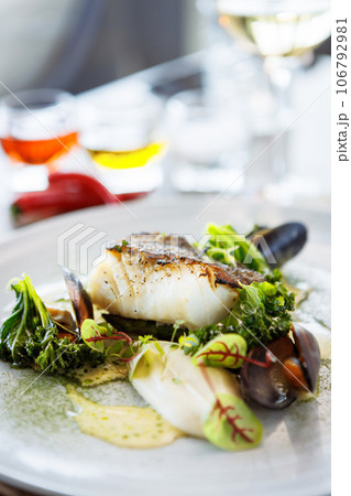 Cod fillet with cauliflower cream, asparagus, clam-wine sauce and mussles. Delicious seafood fish closeup served on a table for lunch in modern cuisine gourmet restaurant 106792981