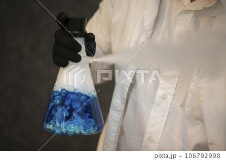 Chemical flask with a blue solution in the hands of a laboratory assistant. Experiences and experiments. Chemical flask with a blue solution in the hands of a laboratory assistant. Experiences and experiments. 106792998