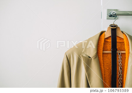 Capsule Wardrobe Autumn 2023, What To Wear This Fall. Autumn fall minimalist wardrobe with orange warm knitted sweater on wooden clothes hanger. Autumn capsule, warm fashion trends 106793389