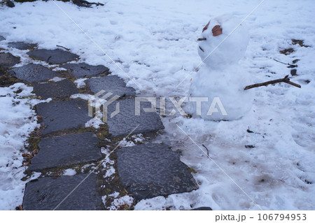 石の道のそばに置かれた雪だるま 106794953