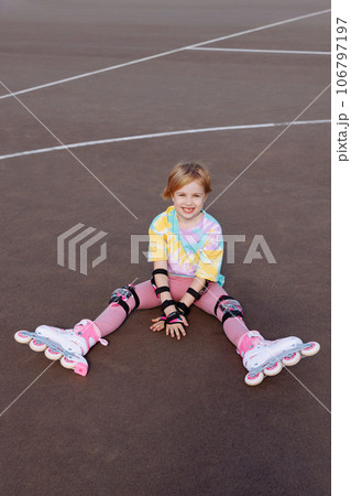 A beautiful little girl learns to roller skate  106797197
