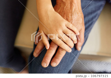 Closeup of hands of young child and old senior man, grandfather and granddaughter hands holding each other, family love and support. Closeup of hands of young child and old senior man, grandfather and granddaughter hands holding each other, family love and support. 106797315