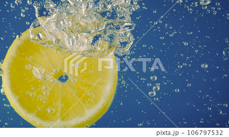 Underwater lemon slice in soda water or lemonade with bubbles. Refreshing soda tonic fizzy cocktail. Close up of lemons and ice cubes in glass. Lime in splashing sparkling water cold drink beverage. Underwater lemon slice in soda water or lemonade with bubbles. Refreshing soda tonic fizzy cocktail. Close up of lemons and ice cubes in glass. Lime in splashing sparkling water cold drink beverage. 106797532