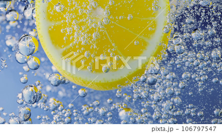 Underwater lemon slice in soda water or lemonade with bubbles. Refreshing soda tonic fizzy cocktail. Close up of lemons and ice cubes in glass. Lime in splashing sparkling water cold drink beverage. Underwater lemon slice in soda water or lemonade with bubbles. Refreshing soda tonic fizzy cocktail. Close up of lemons and ice cubes in glass. Lime in splashing sparkling water cold drink beverage. 106797547