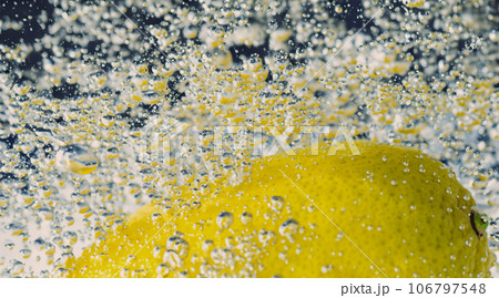 Underwater lemon slice in soda water or lemonade with bubbles. Refreshing soda tonic fizzy cocktail. Close up of lemons and ice cubes in glass. Lime in splashing sparkling water cold drink beverage. Underwater lemon slice in soda water or lemonade with bubbles. Refreshing soda tonic fizzy cocktail. Close up of lemons and ice cubes in glass. Lime in splashing sparkling water cold drink beverage. 106797548