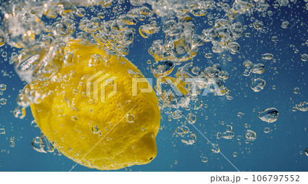 Underwater lemon slice in soda water or lemonade with bubbles. Refreshing soda tonic fizzy cocktail. Close up of lemons and ice cubes in glass. Lime in splashing sparkling water cold drink beverage. Underwater lemon slice in soda water or lemonade with bubbles. Refreshing soda tonic fizzy cocktail. Close up of lemons and ice cubes in glass. Lime in splashing sparkling water cold drink beverage. 106797552