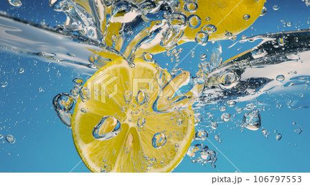 Underwater lemon slice in soda water or lemonade with bubbles. Refreshing soda tonic fizzy cocktail. Close up of lemons and ice cubes in glass. Lime in splashing sparkling water cold drink beverage. Underwater lemon slice in soda water or lemonade with bubbles. Refreshing soda tonic fizzy cocktail. Close up of lemons and ice cubes in glass. Lime in splashing sparkling water cold drink beverage. 106797553