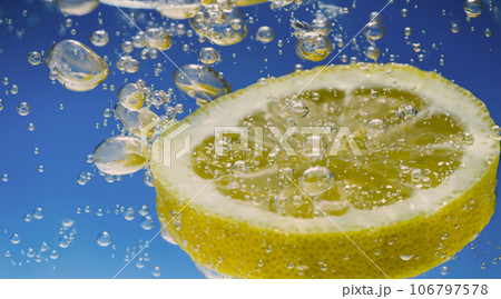 Underwater lemon slice in soda water or lemonade with bubbles. Refreshing soda tonic fizzy cocktail. Close up of lemons and ice cubes in glass. Lime in splashing sparkling water cold drink beverage. Underwater lemon slice in soda water or lemonade with bubbles. Refreshing soda tonic fizzy cocktail. Close up of lemons and ice cubes in glass. Lime in splashing sparkling water cold drink beverage. 106797578