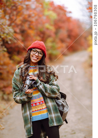 Young woman- tourist taking pictures in autumn forest. Rest, relaxation, tourism, lifestyle concept. Young woman- tourist taking pictures in autumn forest. Rest, relaxation, tourism, lifestyle concept. 106798308
