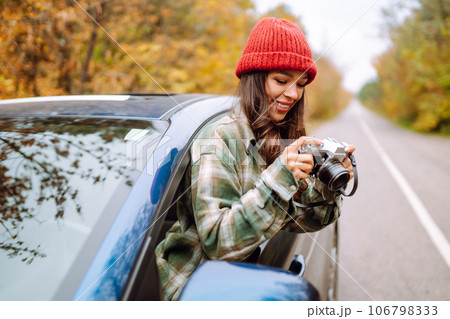 Happy woman takes pictures on camerafrom car window Enjoying autumn weather. Rest, lifestyle concept Happy woman takes pictures on camerafrom car window Enjoying autumn weather. Rest, lifestyle concept 106798333