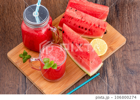 Watermelon smoothie in a glass cup and jar with a lid and straw. 106800274