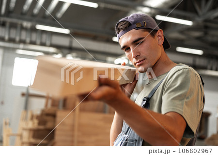 Young carpenter man looking and choosing wood plank at workshop in carpenter wood factory Young carpenter man looking and choosing wood plank at workshop in carpenter wood factory 106802967