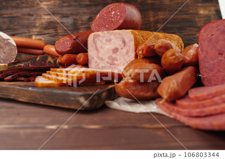 Assortment of different sausages laid out on brown wooden background 106803344