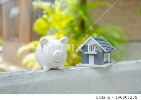 piggybank and the home model stands in front of home background, Saving money for buy real Estate concept piggybank and the home model stands in front of home background, Saving money for buy real Estate concept 106805239