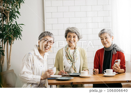 カフェでお茶をするシニア仲間・スマホを見るシニアの女性たち カフェでお茶をするシニア仲間・スマホを見るシニアの女性たち 106806640