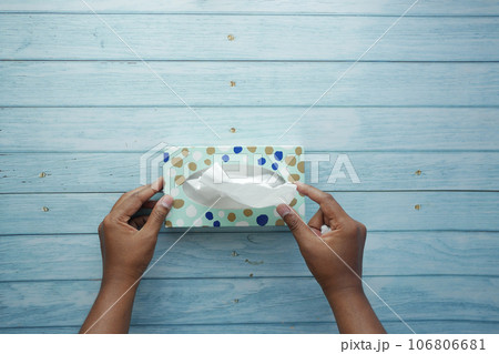 hand pull out a piece of tissue from tissue paper box  106806681