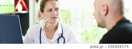 Female doctor listens attentively to patient's story about his illness, sitting at hospital table. 106808574