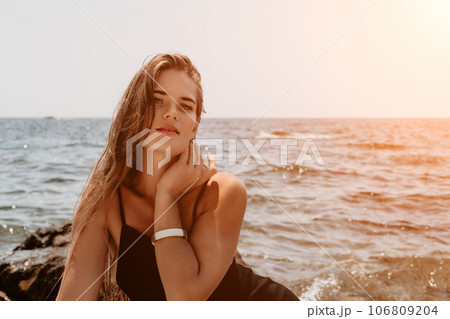 Woman summer travel sea. Happy tourist in hat enjoy taking picture outdoors for memories. Woman traveler posing on the beach at sea surrounded by volcanic mountains, sharing travel adventure journey 106809204