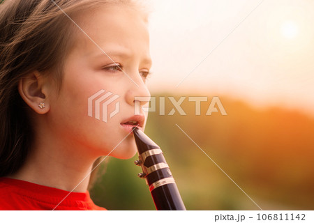 Young attractive girl playing clarinet, ebony in fall park 106811142