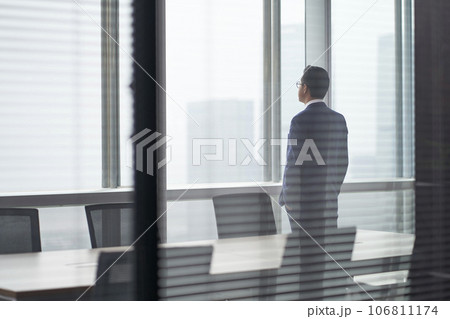 asian corporate executive standing in front of window thinking asian corporate executive standing in front of window thinking 106811174