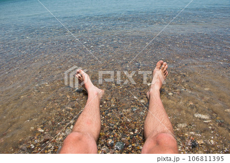 Sea waves washing man's feet 106811395
