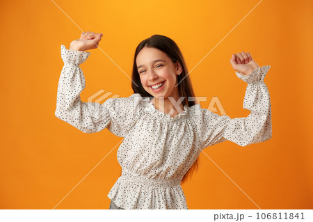 Portrait of a joyful happy teenage girl celebrating success on yellow background Portrait of a joyful happy teenage girl celebrating success on yellow background 106811841