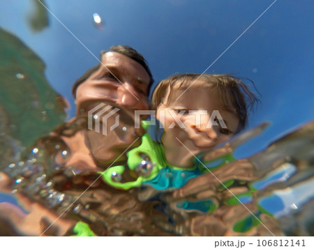 Underwater view of a father and her daughter with distorted faces having fun at the sea 106812141
