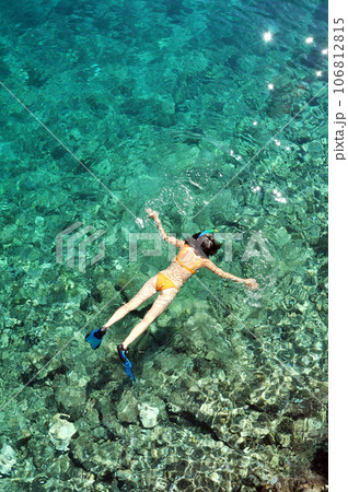 Young woman in swimsuit snorkeling in clear shallow tropical sea over coral reefs Young woman in swimsuit snorkeling in clear shallow tropical sea over coral reefs 106812815