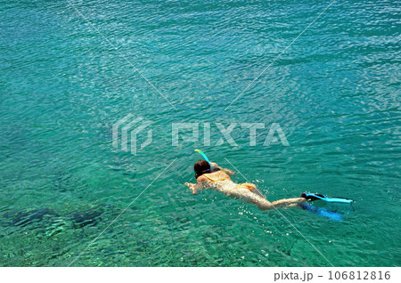 Young woman in swimsuit snorkeling in clear shallow tropical sea over coral reefs Young woman in swimsuit snorkeling in clear shallow tropical sea over coral reefs 106812816