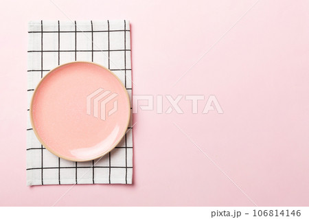 Top view on colored background empty round pink plate on tablecloth for food. Empty dish on napkin with space for your design Top view on colored background empty round pink plate on tablecloth for food. Empty dish on napkin with space for your design 106814146