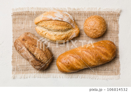 Assortment of freshly baked bread with napkin on rustic table top view. Healthy unleavened bread. French bread Assortment of freshly baked bread with napkin on rustic table top view. Healthy unleavened bread. French bread 106814532