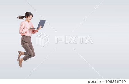 ノートパソコンを使いながらジャンプするミドル女性 106816749