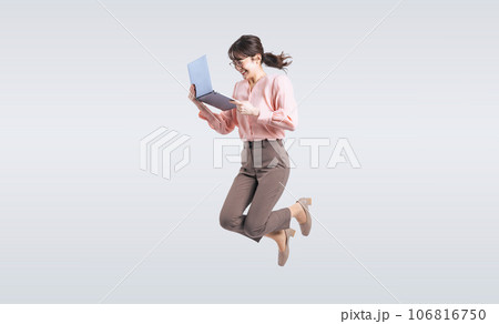 ノートパソコンを使いながらジャンプするミドル女性 106816750