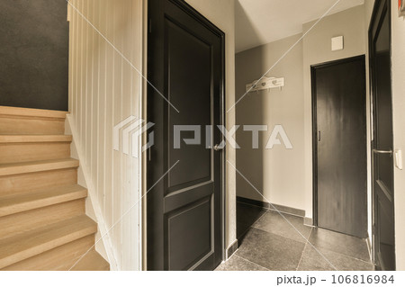 a hallway with black doors and wooden steps leading up to the second floor in an apartment or condo, which is for sale a hallway with black doors and wooden steps leading up to the second floor in an apartment or condo, which is for sale 106816984
